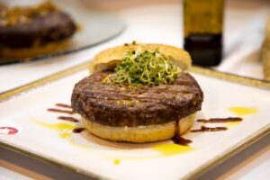 A mouth-watering hamburger topped with fresh sprouts, served on a plate.