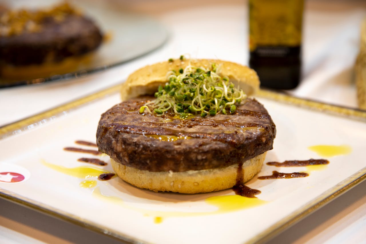 A mouth-watering hamburger topped with fresh sprouts, served on a plate.